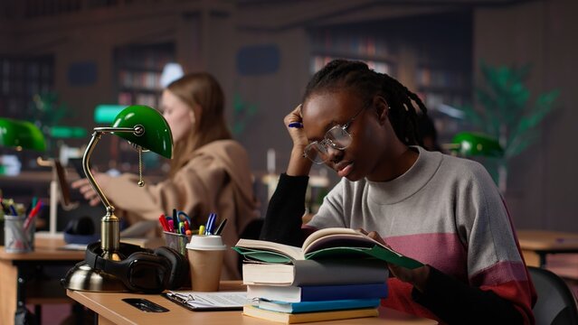 Exhausted student falling asleep while she reads for periodical exams at the college, working hard for diploma with excellent marks. Tired pupil studying all night before first grade. Camera A.