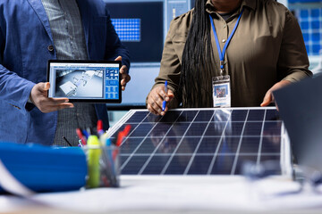 Investors meeting with photovoltaics factory manager to review solar cell designs using tablet....