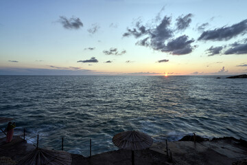 Beach with umbrellas and sunbeds during sunset