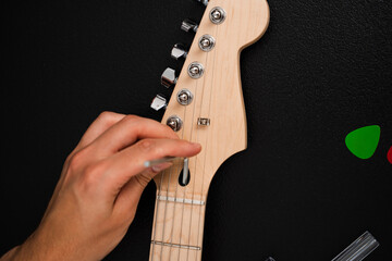 Guitar Adjustment with Hex Key. Guitarist uses a hex key to adjust bridge saddles and string height. Guitar strings are adjusted with a hex key at the bridge for accurate intonation and comfort.