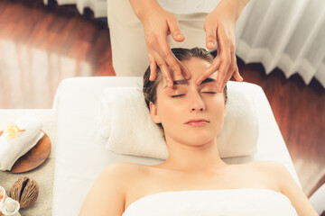 Caucasian woman enjoying relaxing anti-stress head massage and pampering facial beauty skin recreation leisure in dayspa modern light ambient at luxury resort or hotel spa salon. Quiescent