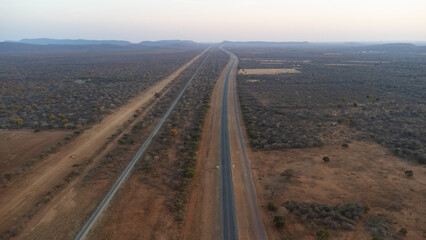 A long straight road cutting through a dry, rural landscape from above