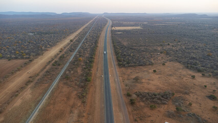 Aerial view of a long straight road cutting through a dry, rural landscape