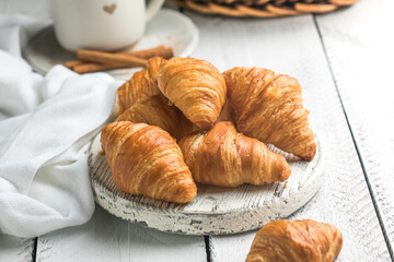 Fresh croissants on white wooden boards, flaky buttery pastry, rustic breakfast