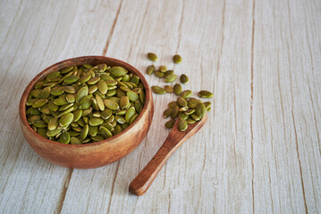 Pepita pumpkin seeds in bowl with wooden spoon