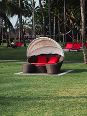 Outdoor rattan sofa with red cushions in tropical resort