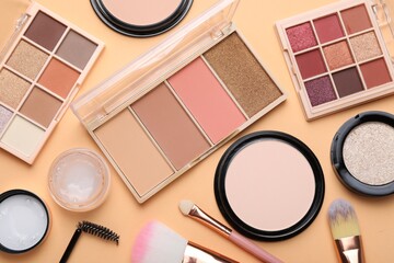 Colorful eyeshadow palettes, other cosmetic products, makeup applicator and brushes on beige...