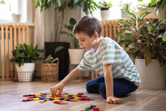 A child plays with geometric shapes and makes a colorful circular mandala pattern from a mosaic.