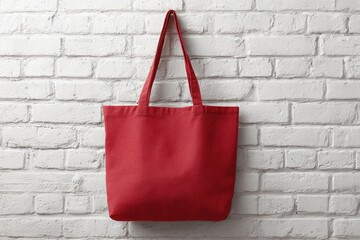 Red tote bag hanging on a white brick wall