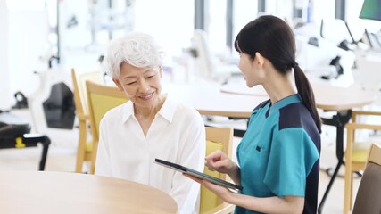 タブレットで健康チェックをするアジア人介護士