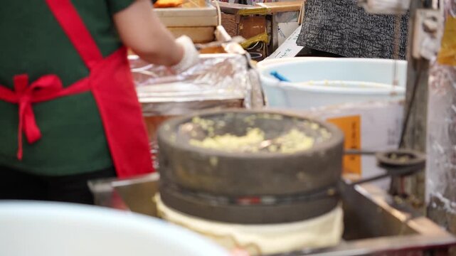 A scene of mung beans being ground with a millstone at a market stall