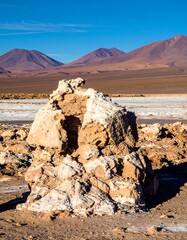 A weathered rock formation stands out against a vast, desert landscape