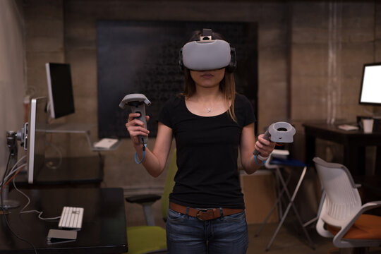 Asian woman wearing casual t-shirt and jeans using VR headset and motion controllers in tech lab