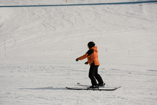 Male skier performing sideways glide across groomed ski run with helmet, goggles, copy space