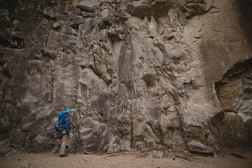 Senior male hiker exploring canyon wearing insulated jacket and boots carrying backpack, copy space