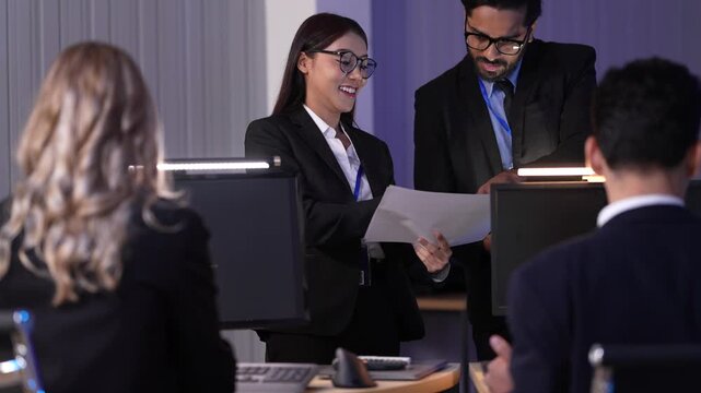 Two data analysts, a man and a woman, review technical specifications for a new software project, pointing at key metrics on a report during a late-night strategy session.