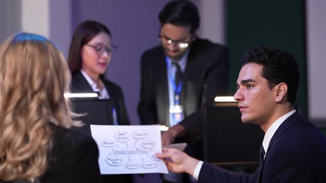 A marketing team leader presents a campaign workflow diagram, outlining the customer journey and key performance indicators (KPIs) for an upcoming product launch in a strategy meeting.