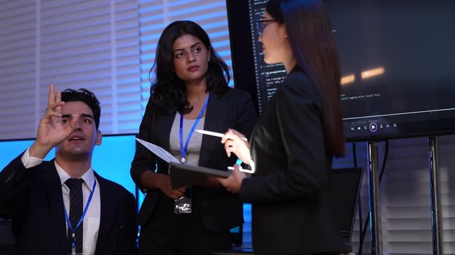 A software developer presents her AI project to her company. She uses a large screen to explain the coding and technology behind her new artificial intelligence program.