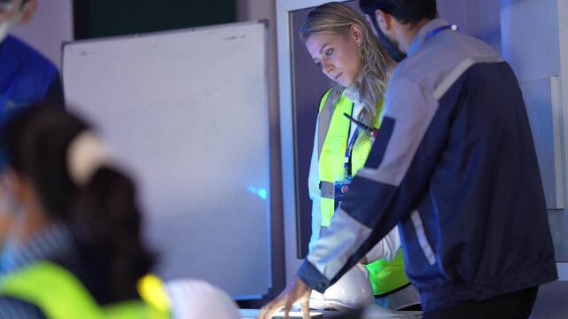 A team of civil engineers and architects reviews blueprints on a light table in a site office. They are coordinating the construction logistics and project timeline for a new build.