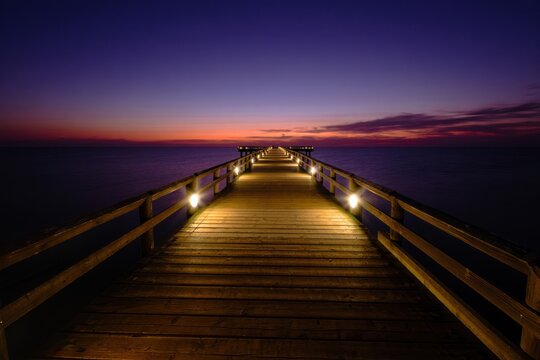 Enchanting wooden pier at twilight, ideal for travel blogs, serene home decor, or coastal event invitations.