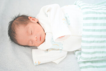 ベッドで眠る新生児0ヶ月の赤ちゃん