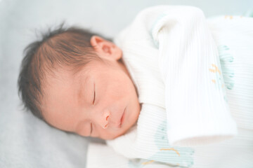 ベッドで眠る新生児0ヶ月の赤ちゃん