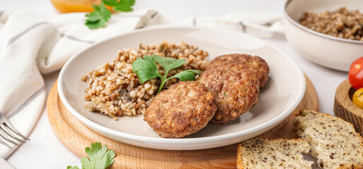 Cutlets with buckwheat, mushrooms and parsley on white table in kitchen