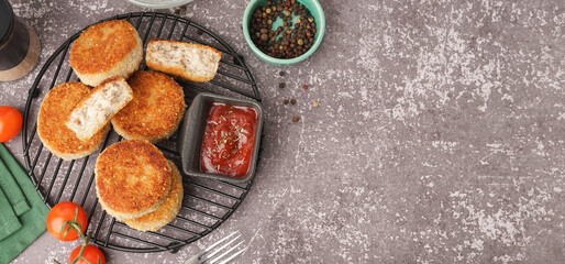 Grid of tasty meat cutlets with sauce on grey background
