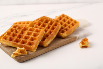 Board with tasty Belgian waffles on white background