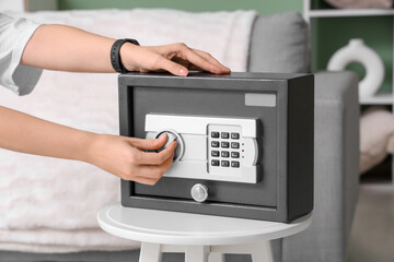 Woman opening safe on table at home, closeup