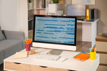 Computer monitor with code and stationery on programmer's desk in office