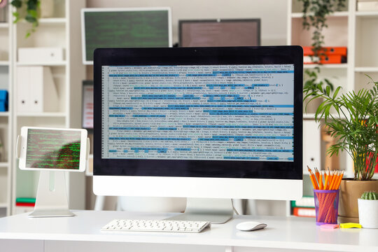 Computer monitor with code and plants on programmer's desk in office