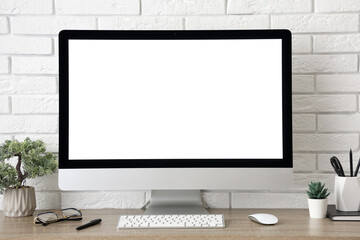 Fototapeta premium Stylish workplace with computer and stationery near white brick wall in light office