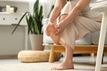 Young woman with flat feet doing massage on sofa at home, closeup