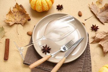 Beautiful table setting with fresh pumpkin, almond nuts, star anise, cinnamon and autumn leaves on brown background