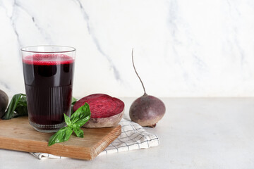 Glass of fresh beet juice with basil and vegetables on white background