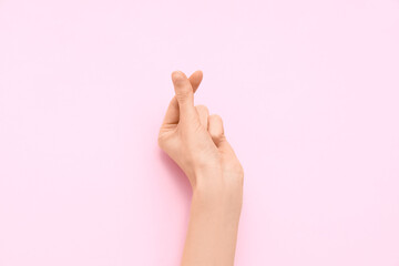 Female hand showing heart gesture on pink background