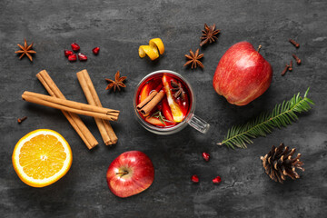 Composition with cup of tasty mulled wine and ingredients on black grunge background