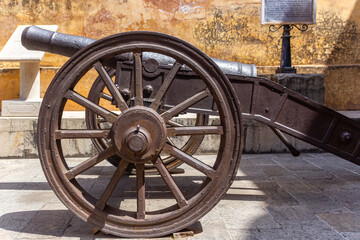 Antique Iron Cannon with Large Wheel in a Palace Courtyard