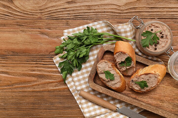 Jar of tasty pate with toasts, parsley and knife on wooden background
