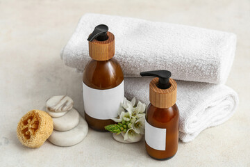 Composition with bottles of cosmetic products, clean towels and spa stones on light background
