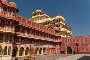 Fototapeta premium Panoramic View of an Inner Courtyard with Red Sandstone Walls and a Tiered Yellow Palace in Rajasthan