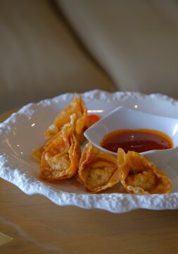 Fried wonton or chinese dumpling on white plate, served with chili sauce. Salty snack , oriental food. Wonton goreng or pangsit goreng