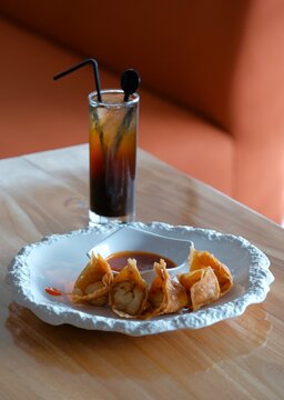 Fried wonton or chinese dumpling on white plate, served with chili sauce. Salty snack , oriental food. Wonton goreng or pangsit goreng. Snack and drink