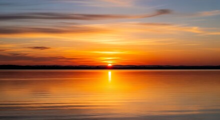 Obraz premium A serene sunset paints the tranquil lake's surface with warm golden hues, casting a peaceful ambiance over the still water.