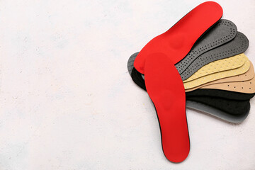 Different orthopedic insoles on light background with space for text