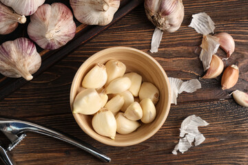 Bowl with fresh garlic cloves on wooden background