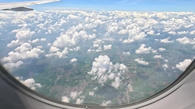 Aerial view from airplane window showing a vast sea of clouds with parts of the airplane wing visible.
