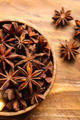 Bowl with anise stars on wooden background, closeup