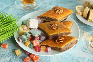 Plate with traditional baklava and Turkish delight on blue table, closeup. Nowruz Bayram celebration